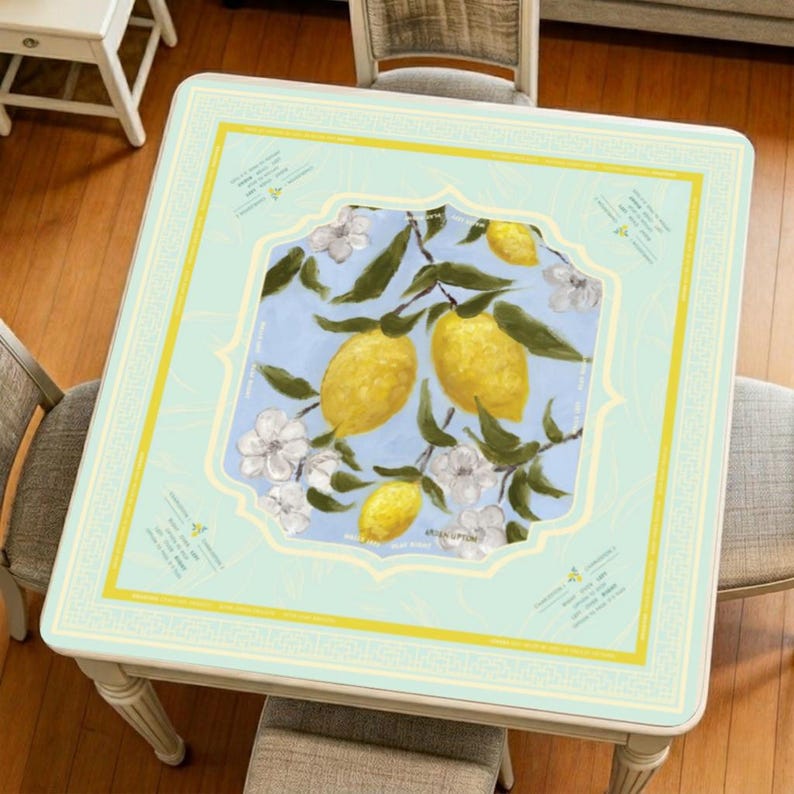 Lemon mahjong mat displayed on a square table, featuring a soft pastel background, bright yellow lemons, white blossoms, and an elegant decorative border for a fresh and artistic look.