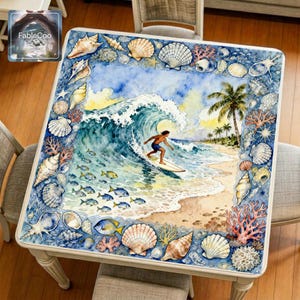 Summer surfing mahjong mat displayed on a square home table, featuring an original coastal design with a surfer riding a curling ocean wave, surrounded by seashells, coral, tropical shoreline details, and soft blue watercolor tones.