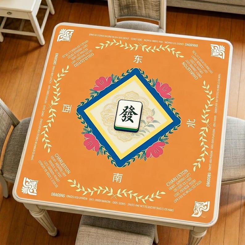 Orange minimalist style mahjong mat displayed on a square table, featuring a clean geometric layout, centered mahjong-inspired artwork, and bright decorative border details.