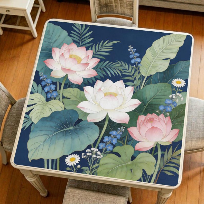 Original pond lotus mahjong mat displayed on a square table, featuring soft pink lotus blossoms, layered green leaves, and a deep blue botanical background.