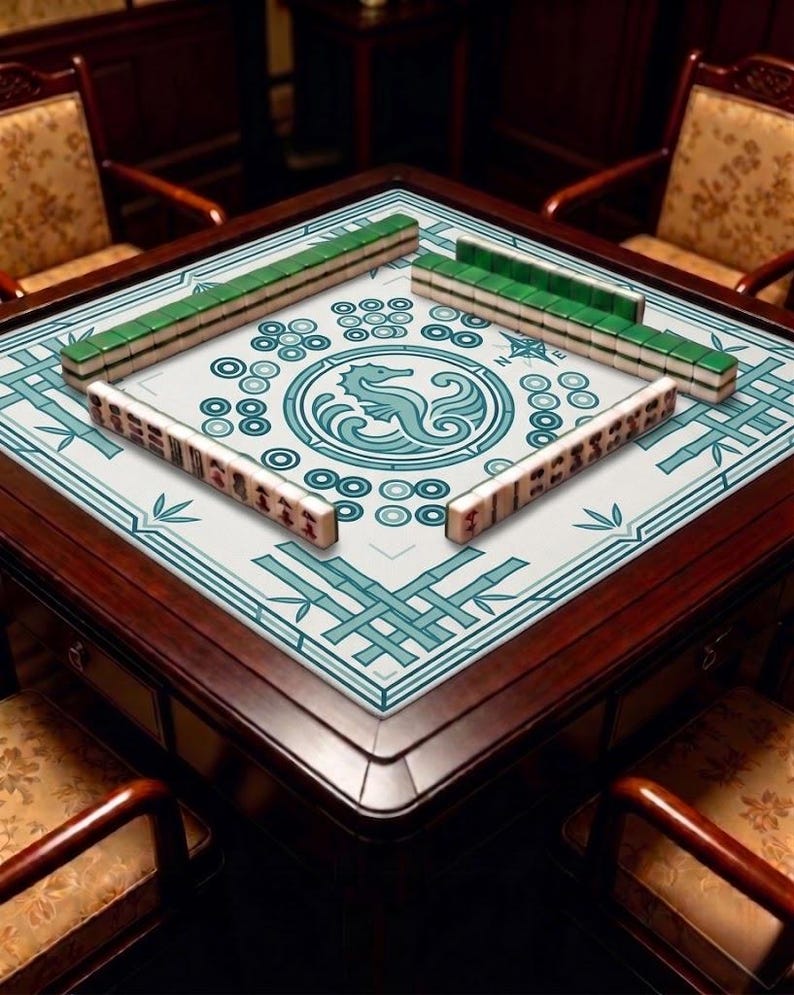 Seahorse themed mahjong mat displayed on a wooden game table with mahjong tiles arranged around the edges, showing the central ocean-inspired emblem and clean decorative border in a cozy indoor setting.