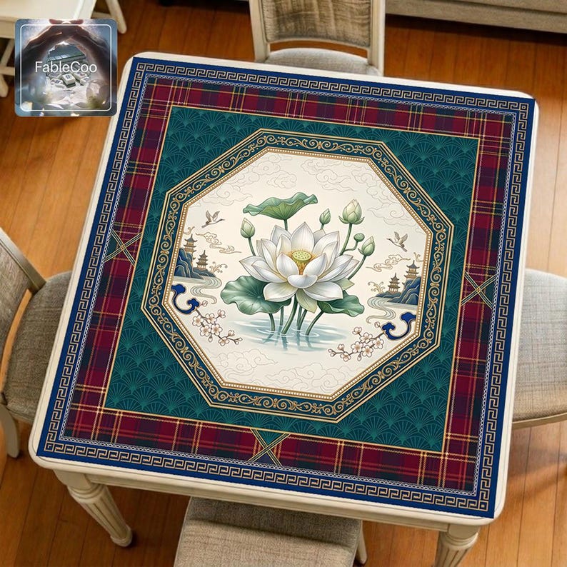 Asian-style mahjong mat displayed on a square home table, featuring an original oriental-inspired lotus scene with blooming white lotus flowers, lotus leaves, soft cloud motifs, distant pavilions, flying birds, and elegant geometric borders in navy blue, deep green, burgundy red, gold, ivory, and blush pink tones.