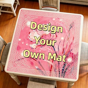 Könnte beinhalten: Ein quadratischer Tisch mit einem rosa Blumendesign und dem Text "Design Your Own Mat". Der Tisch hat einen weißen Rand mit einem geometrischen Muster. Der Tisch ist von Stühlen umgeben.