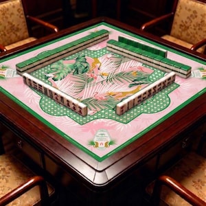 May include: A wooden Mahjong table with green and white tiles arranged on a pink mat. The mat features a tropical design with flamingos, palm leaves, and a green border. The table is surrounded by four wooden chairs.