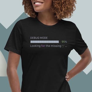 May include: A black short-sleeved t-shirt featuring a graphic print that reads DEBUG MODE with a progress bar at 95% and the text Looking for the missing ';'. The design is printed in white and light green on the center of the chest.