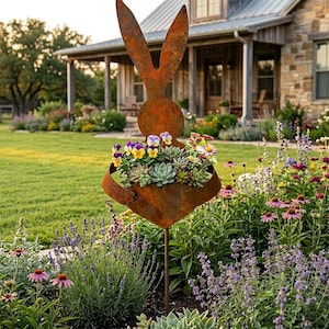 May include: A rusty metal garden stake in the shape of a rabbit holding a planter filled with colorful flowers and succulents. The rabbit has long ears and a round body. The planter is a basket shape. The background is a lush garden with a house.