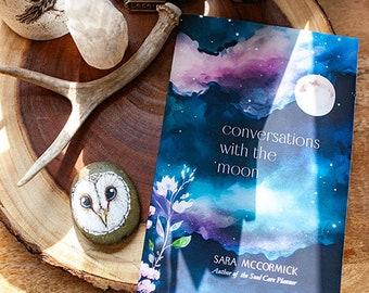 May include: A book titled "Conversations with the 'moon'" by Sara McCormick, author of the Soul Care Planner. The cover features a watercolour painting of a night sky with clouds, stars, and a full moon.