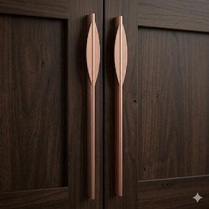 May include: Close-up of two cabinet doors with dark wood grain. Each door has a long, copper-colored handle with a leaf-like design. The handles are vertically aligned, adding a touch of elegance to the wooden doors.