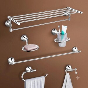 May include: A set of chrome bathroom accessories including a wall-mounted towel shelf with a bar, a soap dish holding a pink bar of soap, a tumbler holder with a toothbrush and toothpaste, a long towel bar, a ring towel holder, and a robe hook.