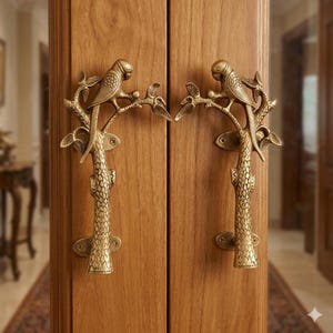 May include: A pair of brass door handles with a parrot and branch design. The handles are mounted on a wooden door. The parrot is perched on a branch, adding a decorative element. The handles are made of brass and have a detailed texture. The door is made of wood.