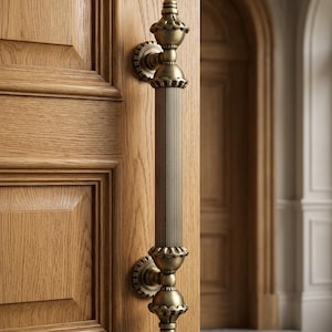 May include: Ornate bronze door pull with vertical ribbed design. The handle features decorative finials and circular backplates, mounted on a light-colored wooden door. The door is partially open, revealing an interior with arched doorways.
