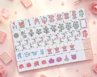 May include: A set of white Mahjong tiles featuring colorful floral, bamboo, and character designs, including tiles marked with the letters N, E, W, S and the word JOKER. The tiles are arranged in a grid, surrounded by scattered pink flower petals.