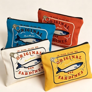 May include: Four rectangular canvas zipper pouches in blue, orange, white, and yellow. Each features a graphic print of a sardine tin with the text "ORIGINAL SARDINES" and "IN PURE OLIVE OIL," accented by a metal pull-tab attached to the zipper.