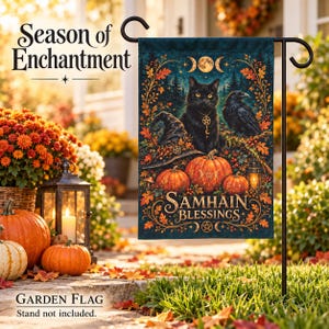 Op de afbeelding: Een rechthoekige tuinvlag met een donkerblauwe achtergrond, voorzien van een zwarte kat met een pentagramketting, een raaf, pompoenen en herfstbladeren. De tekst luidt Season of Enchantment en Samhain Blessings met maanfasen en pentagrammen.