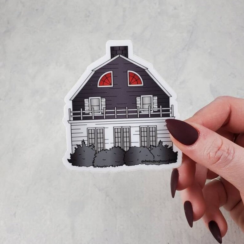 May include: A sticker featuring a black and white illustration of a house with red arched windows. The house has a dark roof and a white facade with multiple windows and a small balcony. The sticker includes the text "@dwindlinghoursglass".