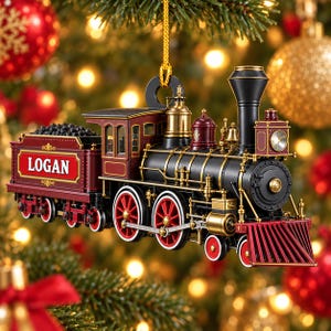 Könnte beinhalten: Ein Weihnachtsbaumschmuck in Form einer alten Dampflokomotive. Der Zug ist in Dunkelrot, Mattschwarz und Metallic-Gold gehalten. An der Seite des Kohletenders befindet sich ein rechteckiges rotes Feld mit dem Namen LOGAN in weißer Schrift.