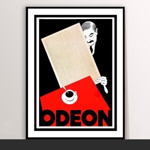 May include: A framed vintage poster with a black and white illustration of a man holding a rectangular object over a red surface. A cup of coffee sits on the red surface, with the word "ODEON" in bold white letters below.