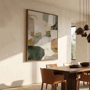 Puede incluir: Impresión artística abstracta en un marco de madera. La obra presenta formas orgánicas en tonos verdes, marrones y beige. La impresión cuelga sobre una mesa de comedor de madera con sillas de cuero, creando un comedor moderno.