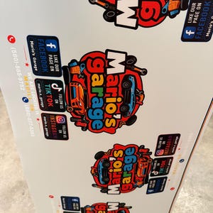May include: A white promotional sign featuring multiple repeating logos for Mario's Garage. Each logo displays a red circular background with a blue car, tools, and the text Mario's Garage. Social media icons for Facebook, TikTok, and Instagram are included.