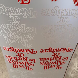 May include: A sheet of adhesive decals featuring the repeating text It will Always be Karbala or Nowhere in both bold red and subtle white lettering. The typography is stylized with a decorative serif font, arranged in multiple rows on a white background.