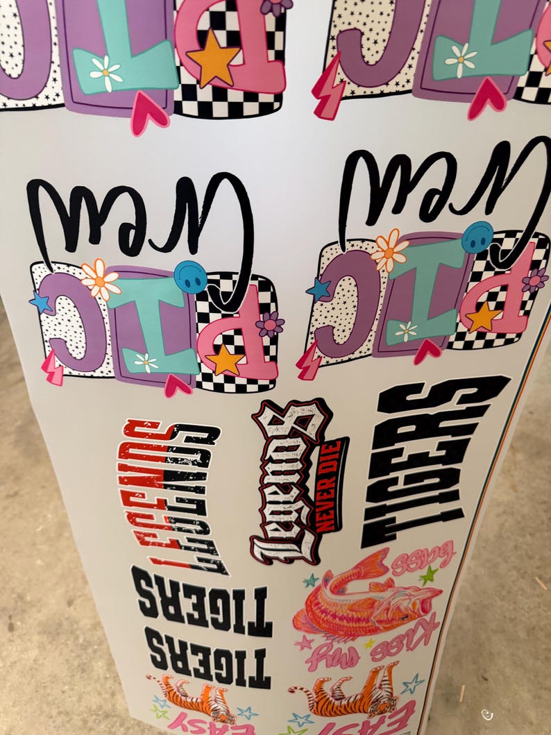 May include: A sheet of assorted vinyl decals featuring colorful designs including the text Picnic Crew in purple and pink, the word Legends in black and red, the word Tigers in black, and a graphic of a fish with the text Kiss My Bass.