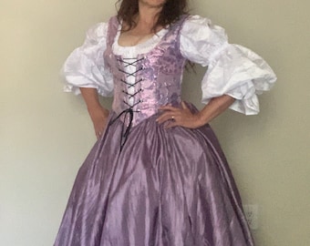 May include: A purple, floor-length gown with a fitted bodice and a lace-up corset. The bodice is decorated with a pink and silver pattern. The gown has a full skirt and is made of a shiny fabric.