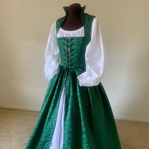 Puede incluir: Un vestido de brocado verde con un corpi&ntilde;o blanco con cordones y una falda blanca debajo. El vestido tiene una falda larga y un corpi&ntilde;o ajustado.