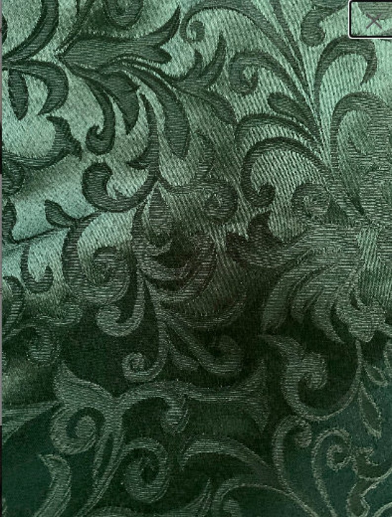 Puede incluir: Una tela verde oscuro con un patr&oacute;n repetido de dise&ntilde;os florales estilizados. La tela tiene una apariencia texturizada, casi tejida.