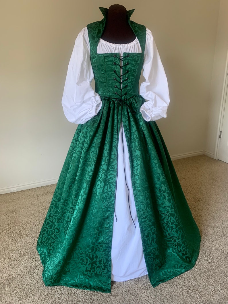 Puede incluir: Un vestido verde y blanco con un corpi&ntilde;o con cordones y una falda completa. El vestido tiene un estampado floral y est&aacute; hecho de una tela suave y fluida.