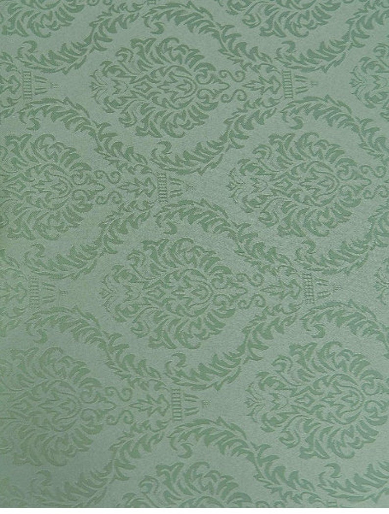 Puede incluir: Una tela verde con un patr&oacute;n damasco repetido. El patr&oacute;n es un dise&ntilde;o floral estilizado con un motivo central que se asemeja a una corona.