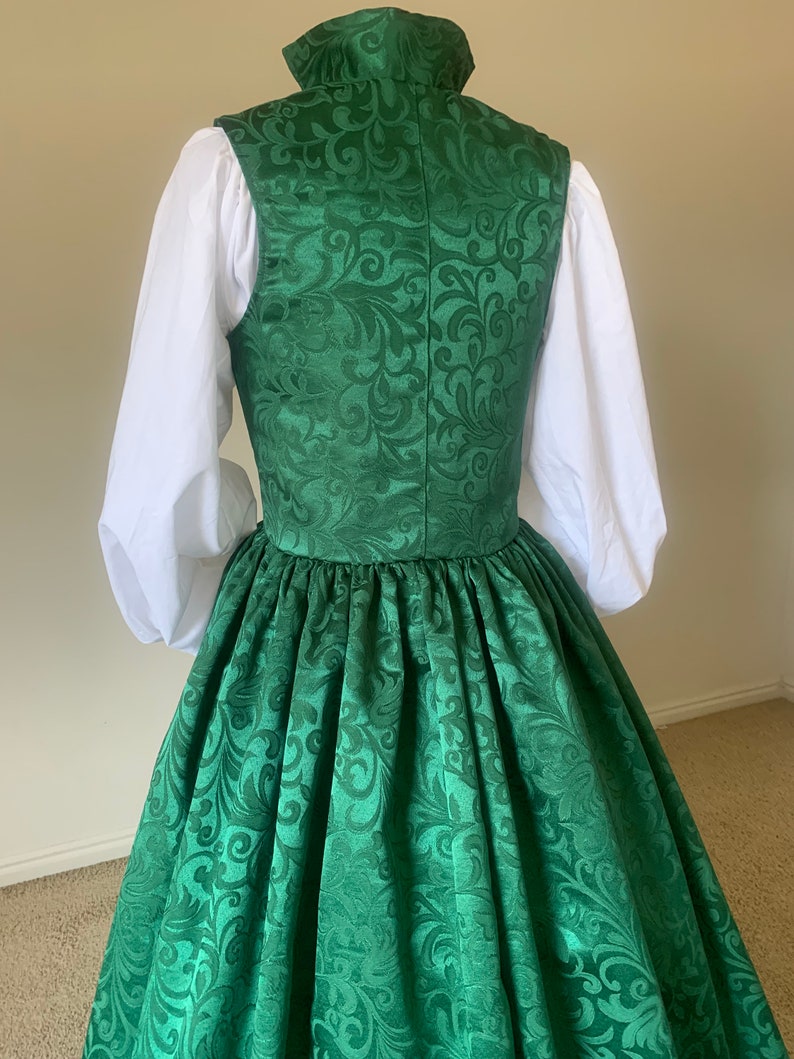 Puede incluir: Un vestido verde con cuello alto y estampado floral. El vestido tiene una falda completa y est&aacute; hecho de una tela sedosa.