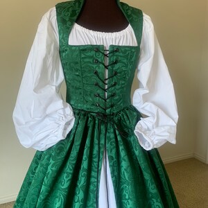 Puede incluir: Un vestido verde y blanco con un corpi&ntilde;o con cordones y una falda completa. El vestido tiene un estampado floral y un cuello alto.