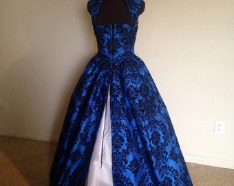 Puede incluir: Un vestido de bola de brocado azul y negro con un corpiño de terciopelo negro y una enagua blanca.