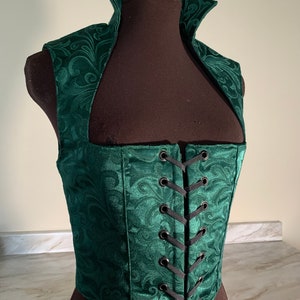 May include: A green velvet corset with a high collar and a lace-up back. The corset has a floral pattern and is made of a soft, luxurious fabric.