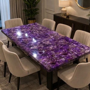May include: A rectangular dining table featuring a polished, deep purple amethyst gemstone slab tabletop with a natural crystalline texture, supported by a black metal frame, surrounded by six light beige upholstered chairs with vertical stitching.