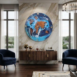 Könnte beinhalten: Eine große, runde Wanduhr mit einem aus Holz gefertigten Weltkarten-Design vor einem Hintergrund aus wirbelndem blau-weißem Harz, das Meereswellen nachahmt. Das Zifferblatt ist mit goldenen Stundenmarkierungen und zentralen Zeigern versehen.