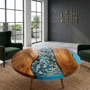Pode incluir: Uma mesa de centro redonda com duas placas de madeira natural e um design de rio central preenchido com resina azul, pedras incrustadas e uma estrela-do-mar. A mesa assenta em quatro pernas de madeira entre duas poltronas estofadas verde-escuras.