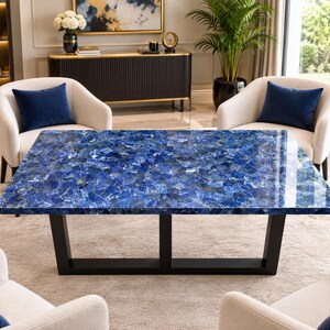 Puede incluir: Una mesa de comedor rectangular con una superficie de piedra preciosa azul pulida con un patrón de mosaico de tonos cobalto y zafiro profundos, sostenida por un marco de metal negro resistente con una base horizontal.