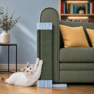 Puede incluir: Un rascador vertical para gatos fijado al lateral de un sofá verde. El poste presenta una sección central envuelta en una cuerda gruesa de color verde oscuro, asegurada en la parte superior e inferior por paneles de madera azul claro con acabado desgastado.