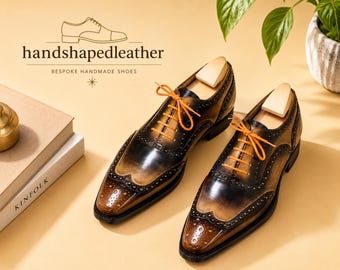 May include: A pair of brown and black leather wingtip oxford shoes with bright orange laces and wooden shoe trees. The text handshapedleather BESPOKE HANDMADE SHOES is visible above the shoes along with a line drawing of a shoe.