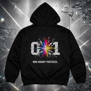 Puede incluir: Sudadera con capucha negra con capucha. La parte trasera presenta el número "01" en blanco, con un diseño de explosión colorido en el centro. Debajo, el texto "NON-BINARY PROTOCOL" en blanco.