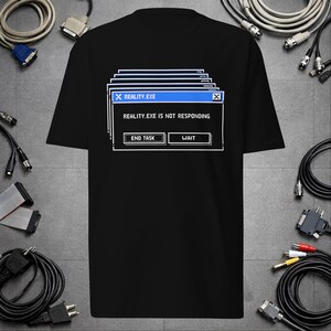 Op de afbeelding: Een zwart t-shirt met korte mouwen en een wit-blauwe afbeelding van een computerfoutmelding. De tekst bovenaan is REALITY.EXE, in het midden staat REALITY.EXE IS NOT RESPONDING, en onderaan staan de knoppen END TASK en WAIT.