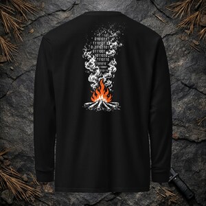 May include: A black long-sleeve shirt featuring a graphic on the back of a campfire with orange and red flames. Above the fire, white smoke rises, transitioning into a vertical column of binary code consisting of ones and zeros in white.
