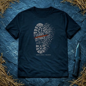 Puede incluir: Camiseta azul marino con un diseño de huella gris. La huella está compuesta en parte por código binario, con las palabras "LEAVE NO TRACE" impresas. Un cuchillo negro con filo dentado es visible a la derecha.