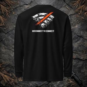 Op de afbeelding: Een zwart shirt met lange mouwen voorzien van een wit, verweerd wifi-icoon dat wordt doorkruist door een dikke oranje diagonale streep. Onder de afbeelding staat de tekst DISCONNECT TO CONNECT in een wit, schreefloos lettertype op de rug.