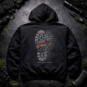 Puede incluir: Sudadera con capucha negra con un diseño gráfico en la espalda. El diseño presenta una huella gris con las palabras "LEAVE NO TRACE" en blanco y rojo, junto con código binario. El texto "ANONYMITY_PROTOCOL // TRACE_DELETED" está debajo.
