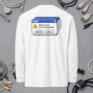 May include: A white long-sleeve shirt featuring a graphic on the back of a stacked computer error window. The window displays the text ERROR, a yellow warning triangle icon, and the text REALITY.EXE IS NOT RESPONDING, with buttons labeled END TASK and WAIT.