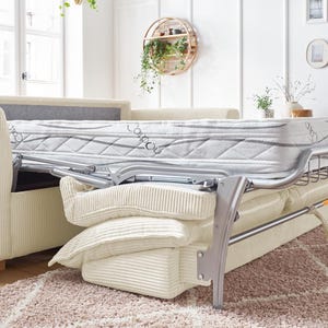 Peut inclure: Un canap&eacute; en velours c&ocirc;tel&eacute; beige avec un cadre de lit gigogne. Le matelas est blanc avec un motif gris. Le canap&eacute; a plusieurs coussins cr&egrave;me et repose sur un tapis brun clair. Le cadre du lit est argent&eacute;.