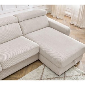 May include: A cream-coloured corduroy sectional sofa. The sofa features a chaise longue and adjustable headrests. It sits on a light rug and wooden flooring, creating a neutral and inviting living space.