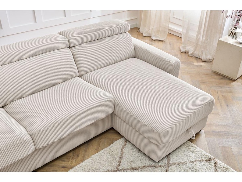 May include: A cream-coloured corduroy sectional sofa. The sofa features a chaise longue and adjustable headrests. It sits on a light rug and wooden flooring, creating a neutral and inviting living space.